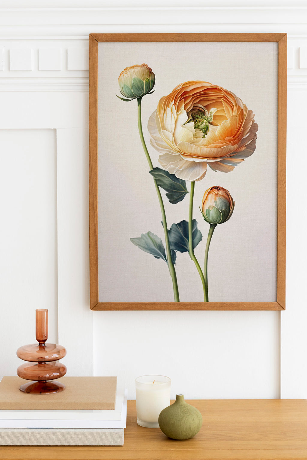 a wooden table with a framed painting of a large orange flower, a small green vase, and a stack of books.