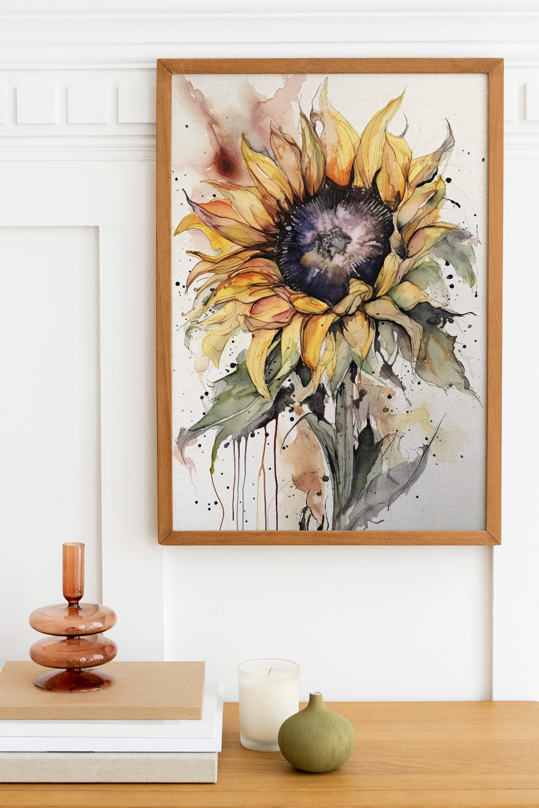 a framed watercolor painting of a vibrant sunflower, hanging on a wall above a wooden table with various decorative items on it.