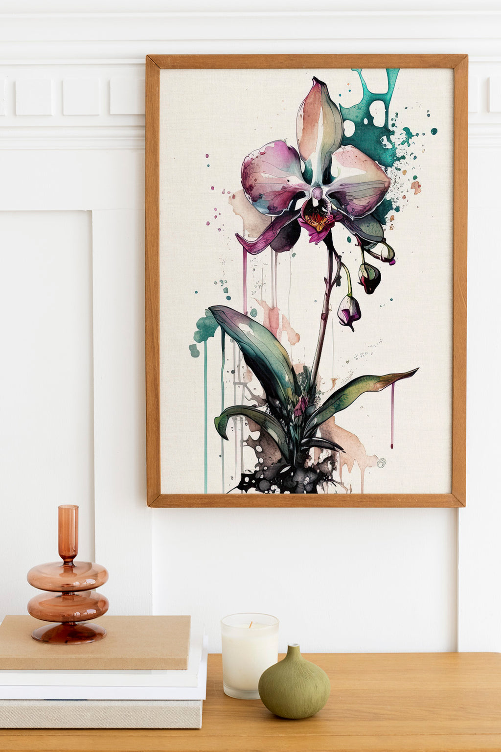 a framed painting of a purple orchid flower hanging on a wall above a wooden table with various decorative items, including a stack of books, a candle, and a small green vase.