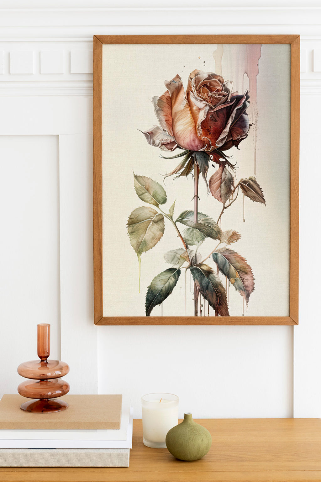 a framed painting of a rose with a watercolor effect, hanging on a wall above a wooden table with various decorative items on it.