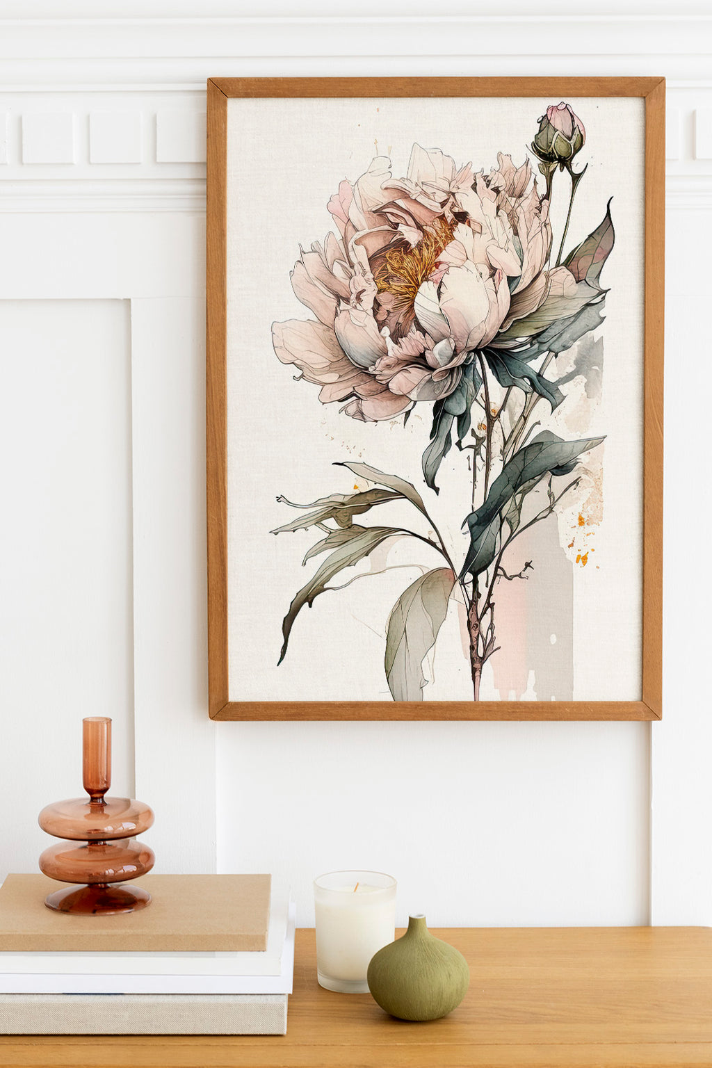 a framed painting of a large, colorful flower on a wall, with a wooden shelf below it holding a stack of books, a small green vase, and a white candle.