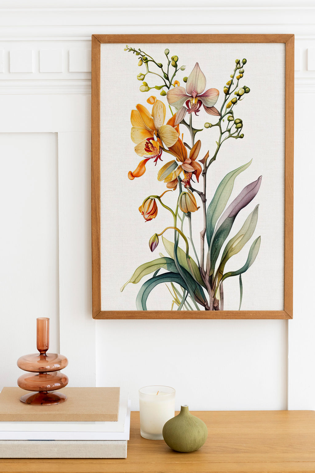 a framed painting of a vibrant floral arrangement hanging on a white wall above a wooden table. The table also holds a stack of books, a small green vase, and a white candle.