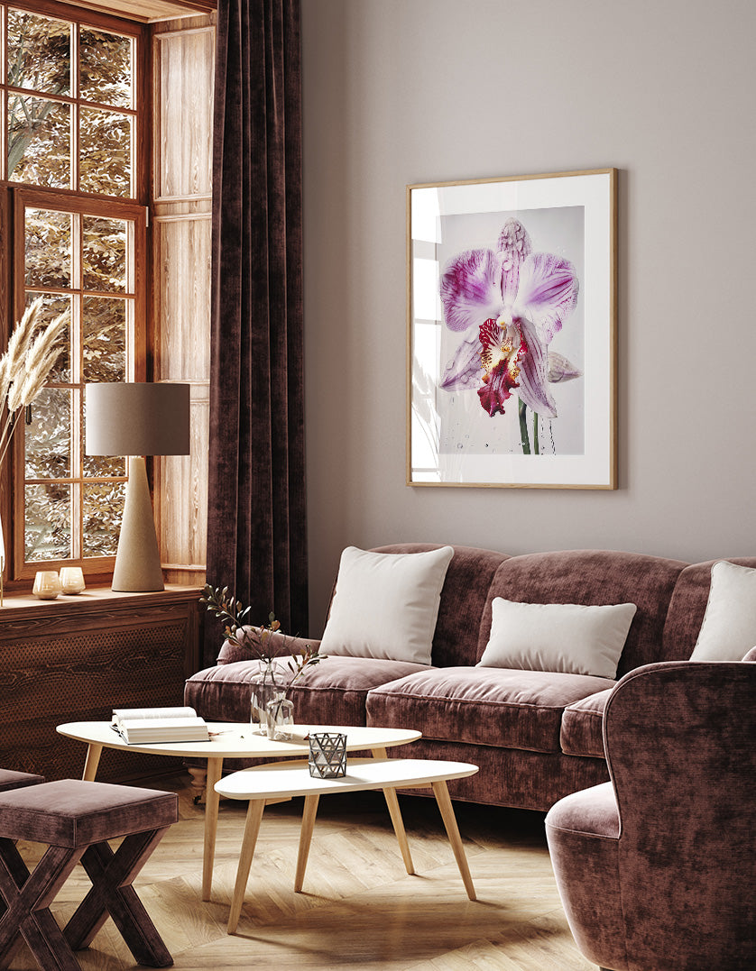 a cozy living room with a large window, a plush purple sofa, a wooden coffee table, and a framed artwork of a purple orchid on the wall.