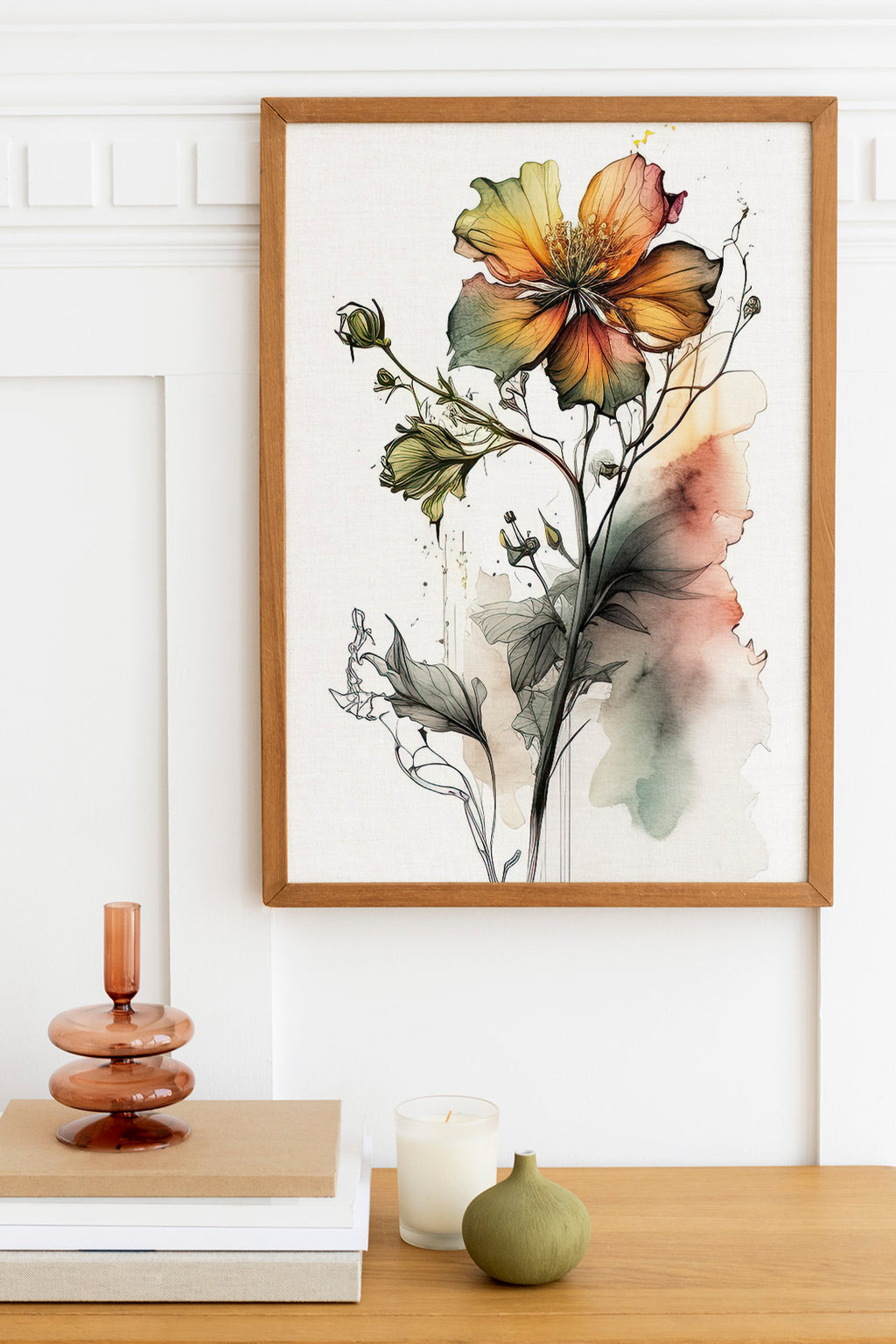 a framed watercolor painting of a vibrant flower, with a wooden frame and a white background. The painting is hung on a wall above a wooden table with various decorative items, including a small vase, a candle, and a stack of books.