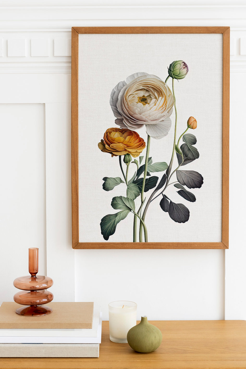 a wooden table with a framed botanical illustration of a white rose, a small green vase, and a stack of books.