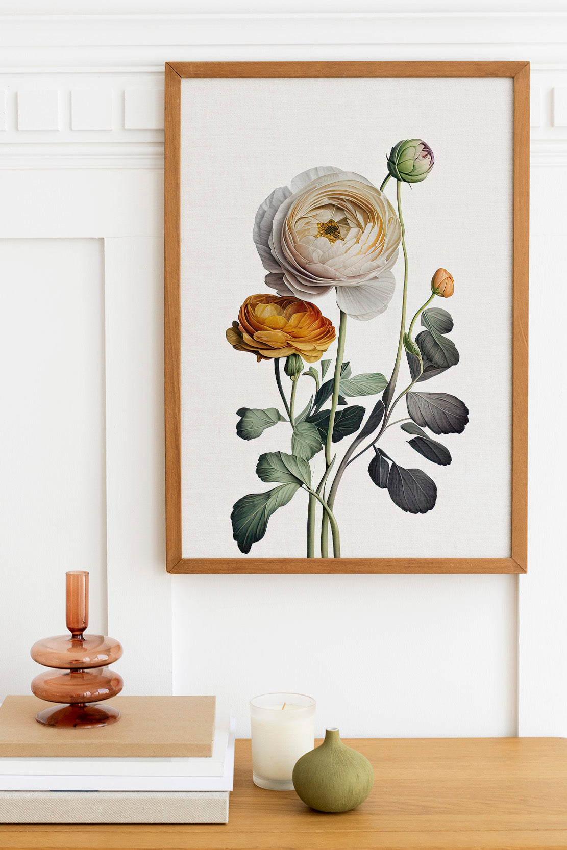 a wooden table with a framed botanical illustration of a white rose, a small green vase, and a stack of books.
