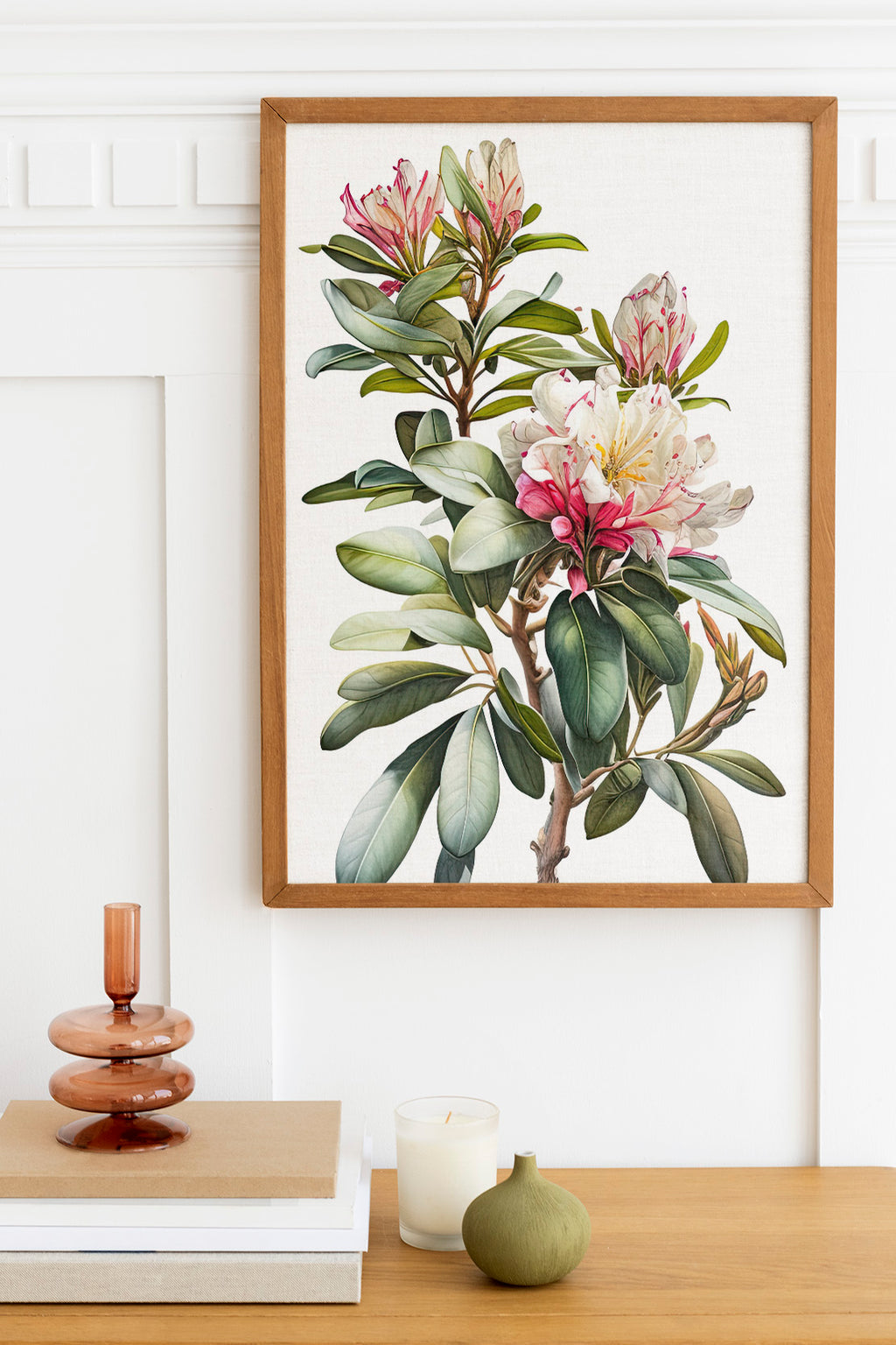a framed botanical illustration of a plant with pink and white flowers, hanging on a white wall above a wooden table with various decorative items.