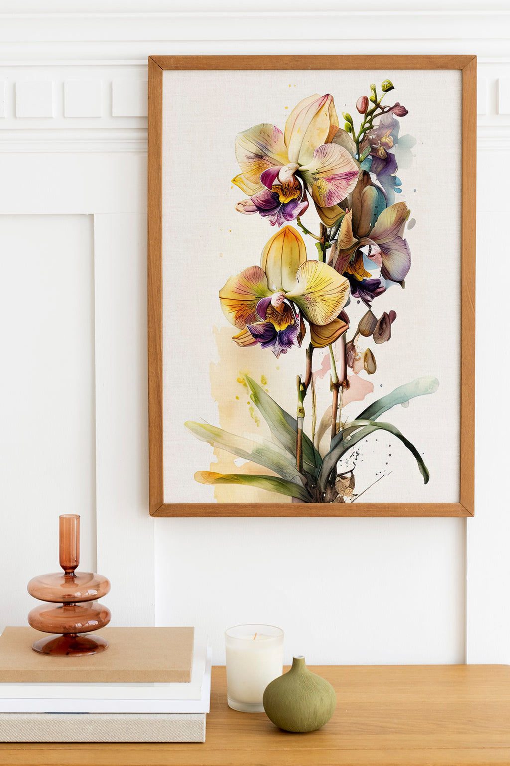 a framed painting of a vibrant orchid plant hanging on a wall above a wooden table. The table has a stack of books, a small green vase, and a white candle.