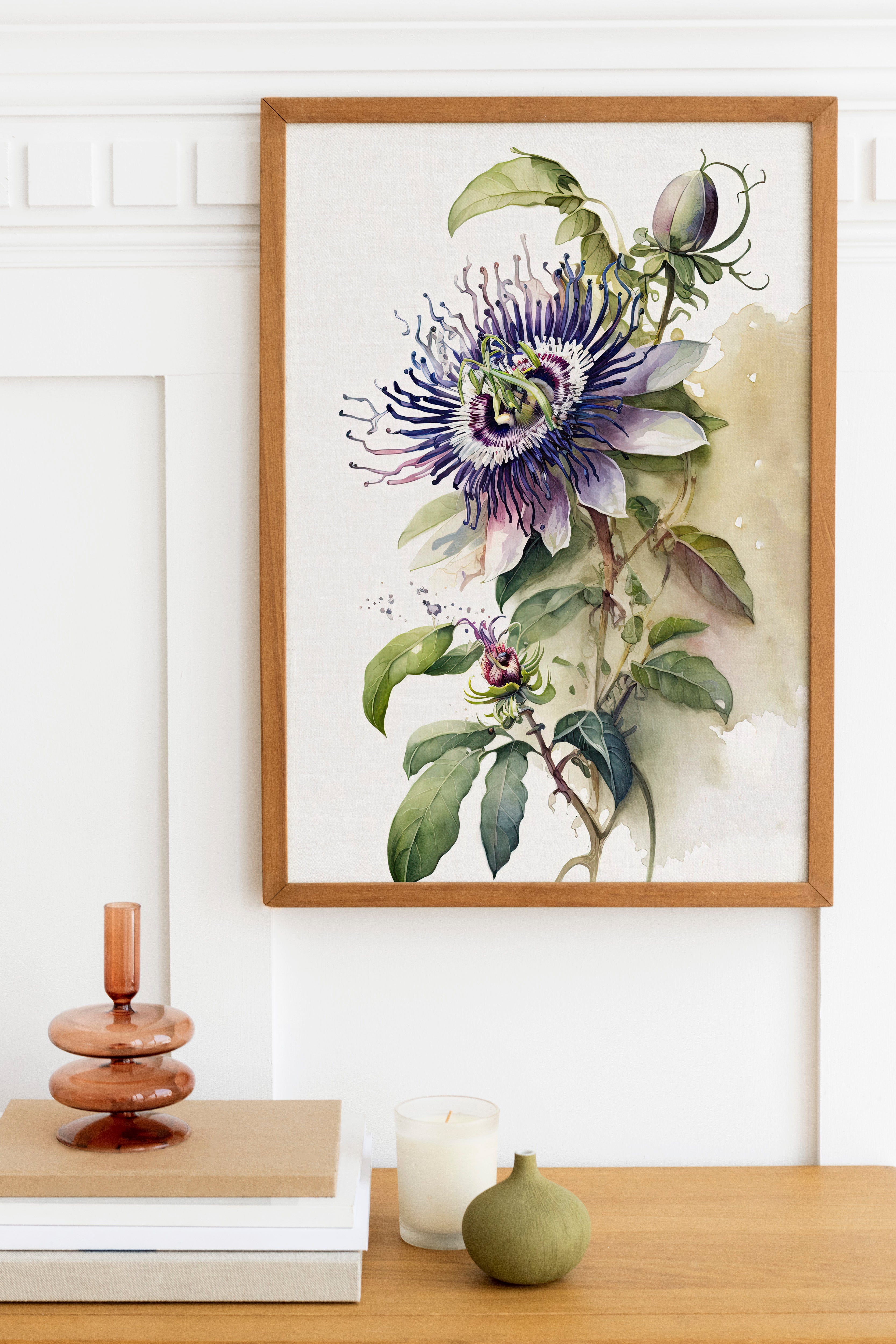 a framed watercolor painting of a purple and green flower on a white wall, with a wooden shelf below it holding a stack of books, a small green vase, and a white candle.